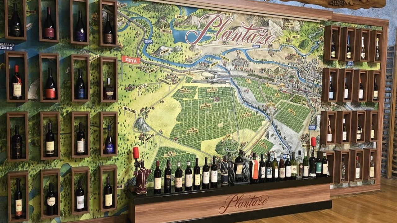 Wine bottles displayed on a wall featuring a large illustrated map of the Plantaže vineyards.