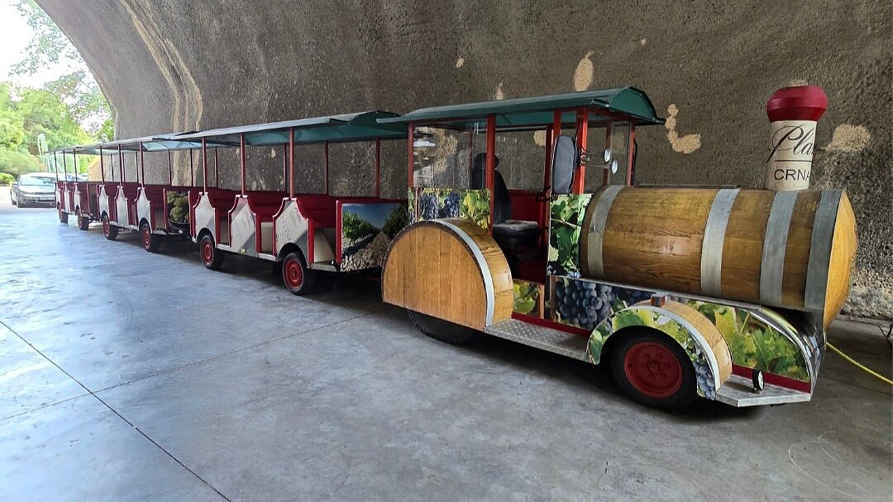 Decorative tour train with a wine-barrel design parked outside the Plantaže wine cellar.